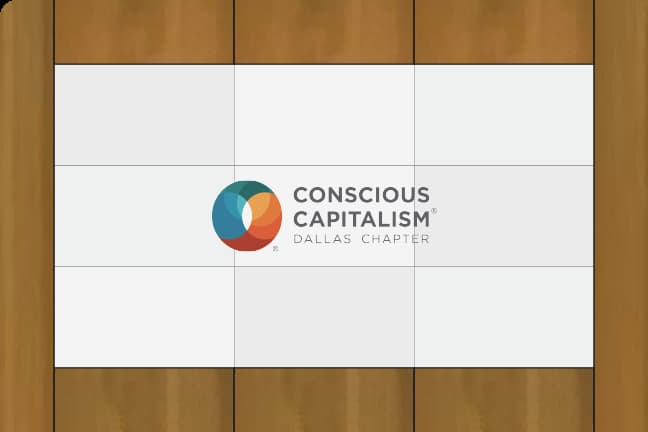 The Conscious Capitalism logo is displayed on a wooden paneled wall