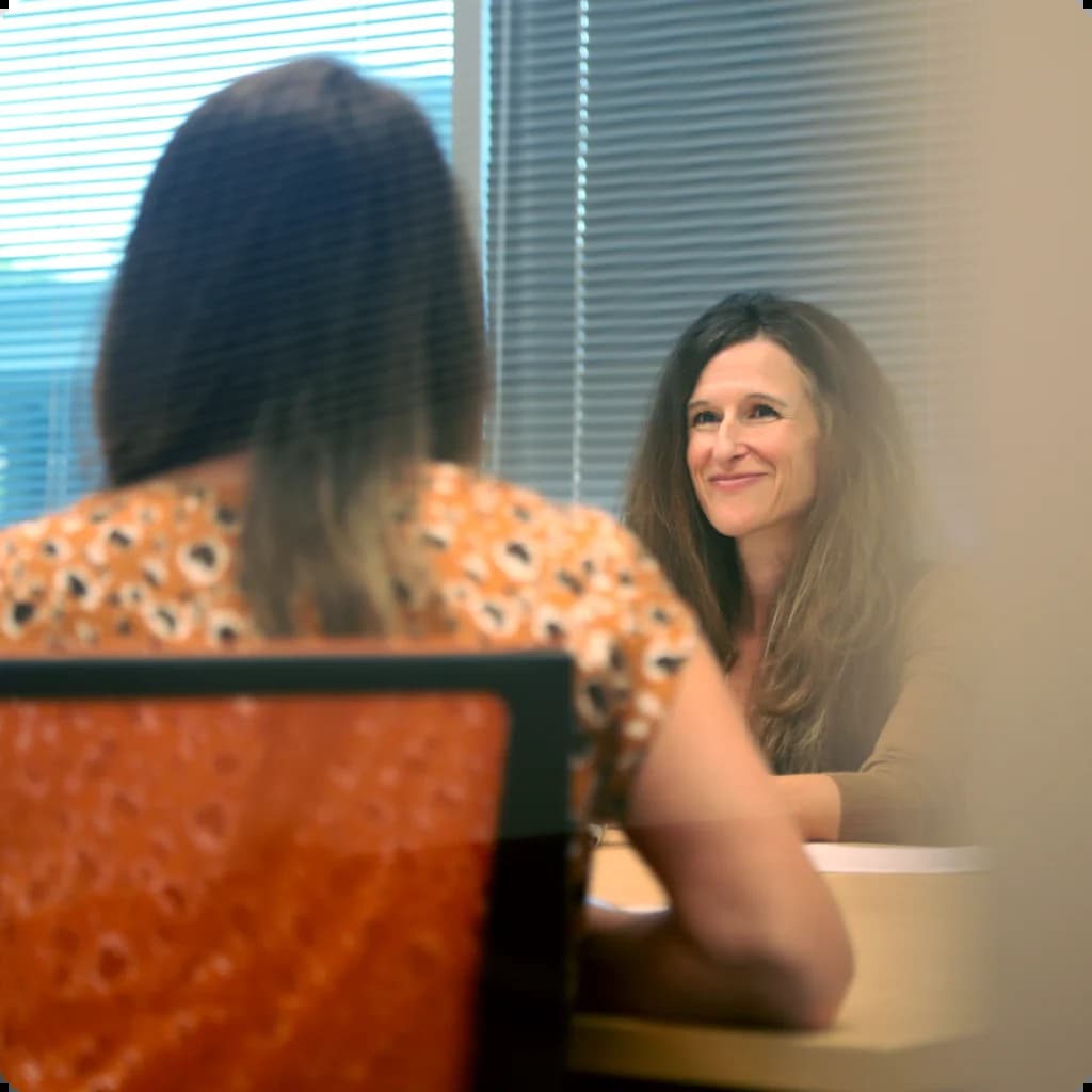 a woman sitting at a table in front of a window