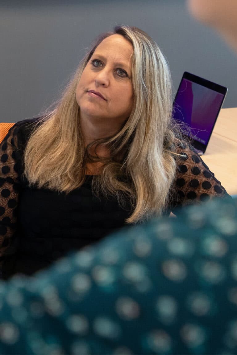 A woman sitting in a chair with a laptop on her lap