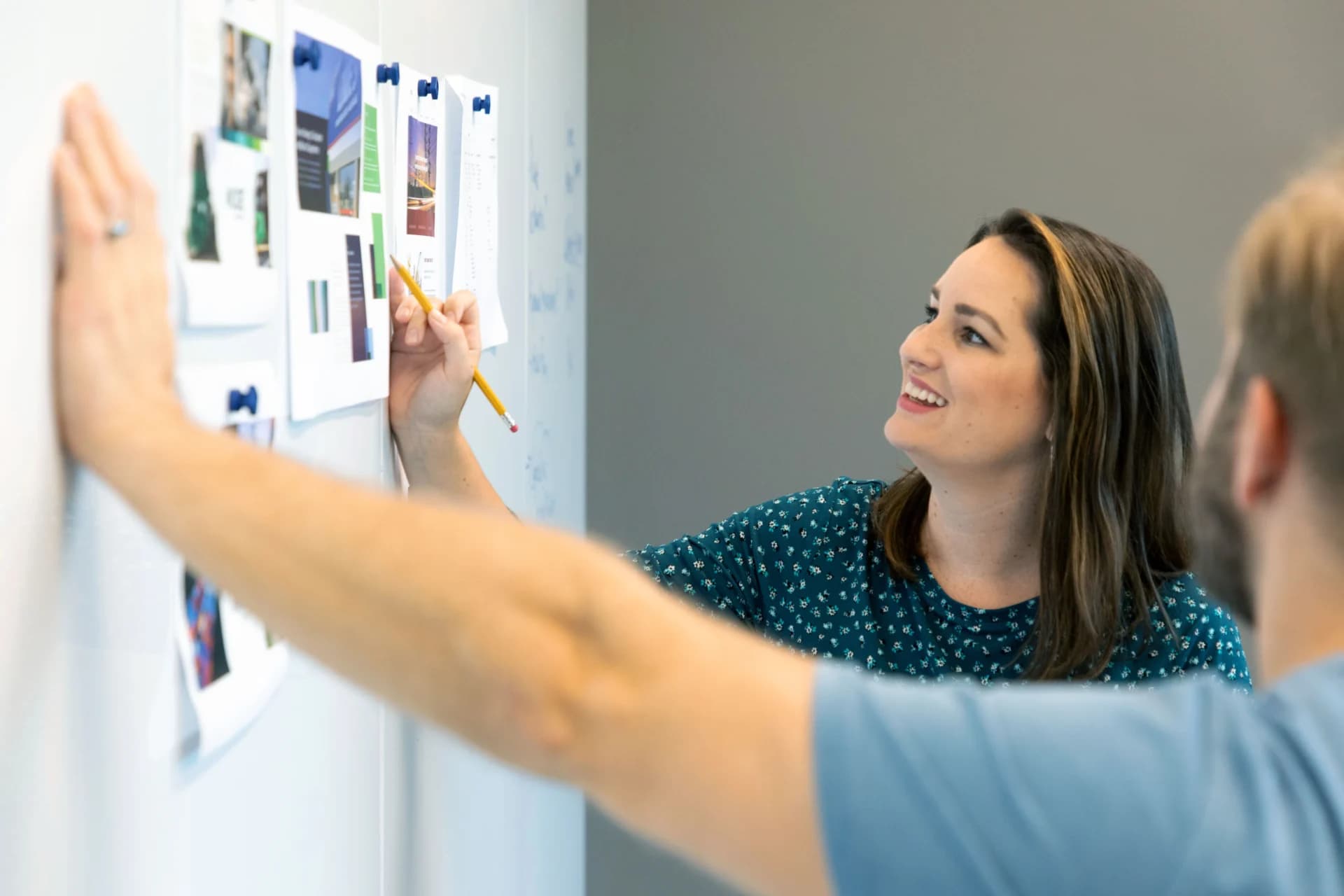 A man and a woman are using a white board to write