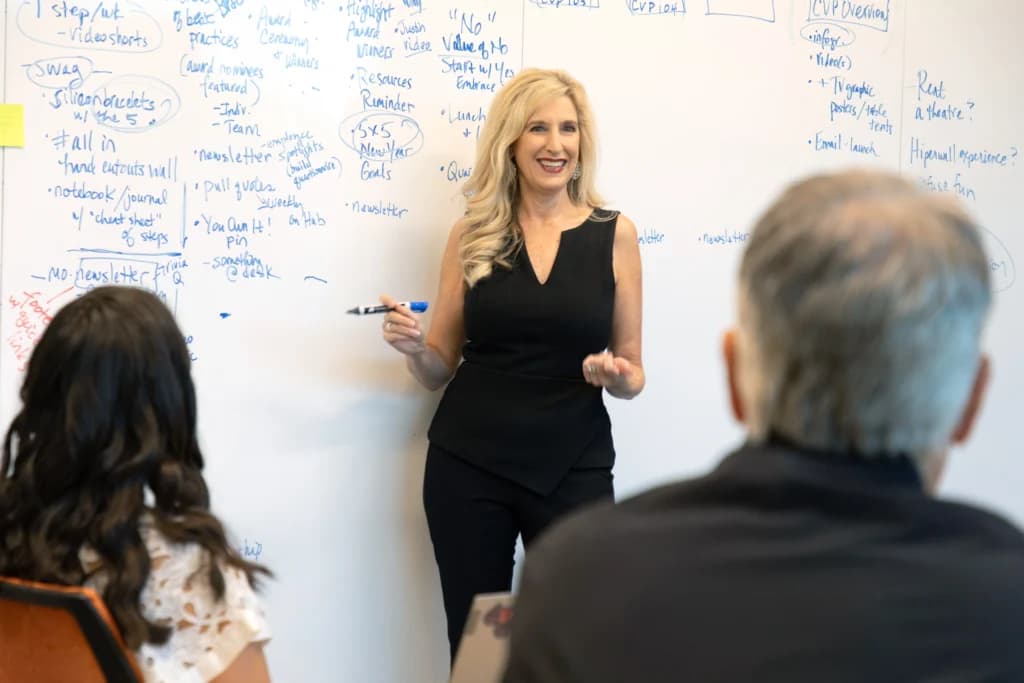 a woman standing in front of a whiteboard with writing on it