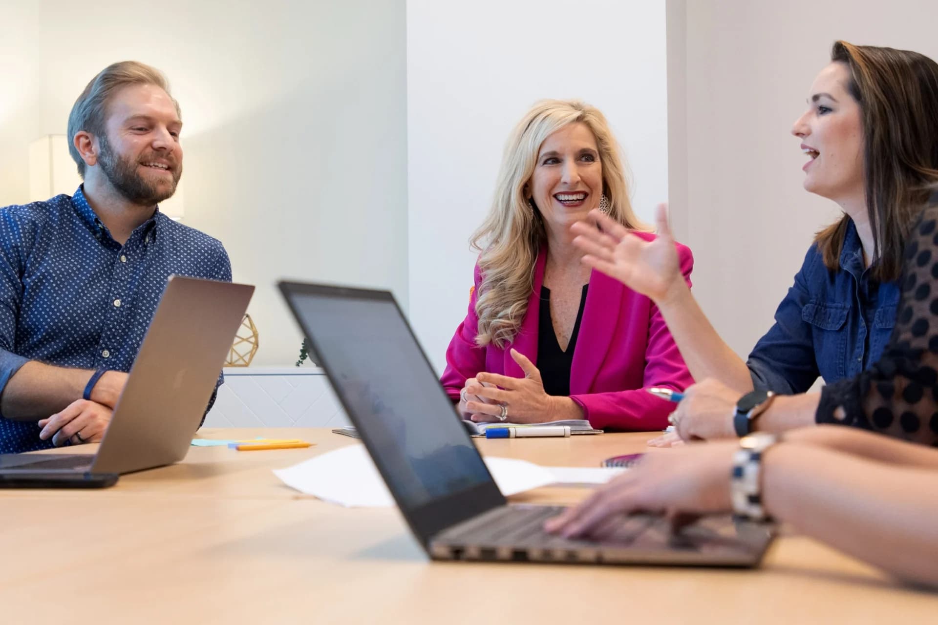 A group of people sitting around a table with laptops